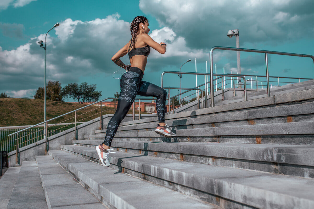 Mulher com roupa de academia subindo escada correndo